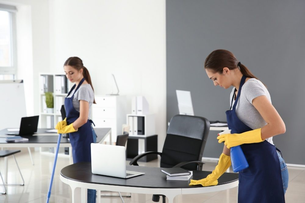 „Curățenie detaliată în birou efectuată de specialiști cu mănuși și soluții profesionale de igienizare.”